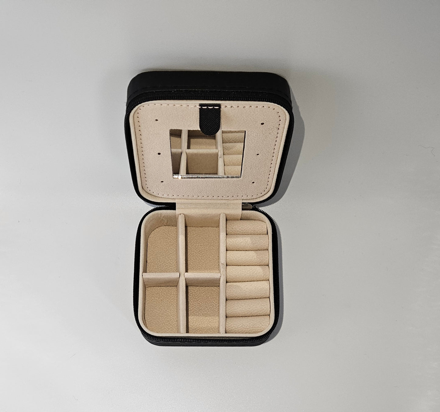 Interior of a travel zip jewellery box with mirror, ring rolls & compartments for earings & small pieces.