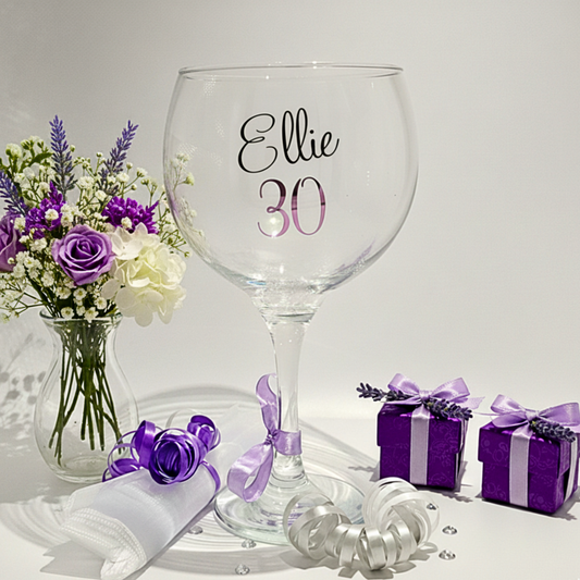 Clear balloon glass with the name 'Ellie' 30 in purple pink vinyl. On a clean background with gift box & flowers
