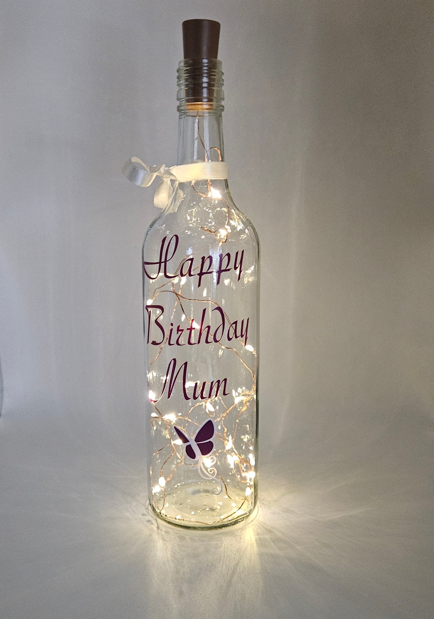 Bespoke personalised LED light-up bottle with a plum purple butterfly decoration, beautifully gift wrapped.