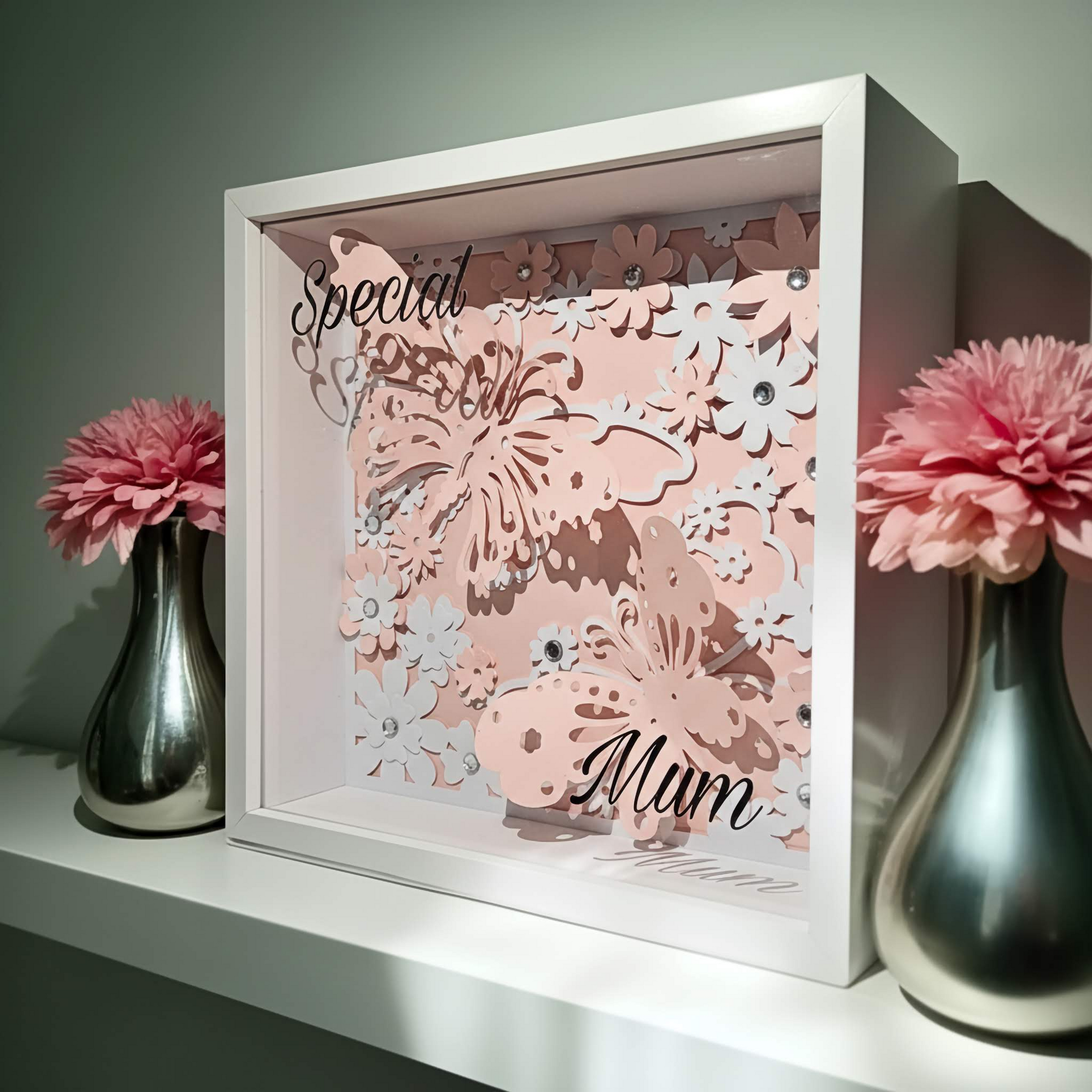 Decorative framed artwork with floral design and 'Special Mum' text, flanked by two silver vases with pink flowers.