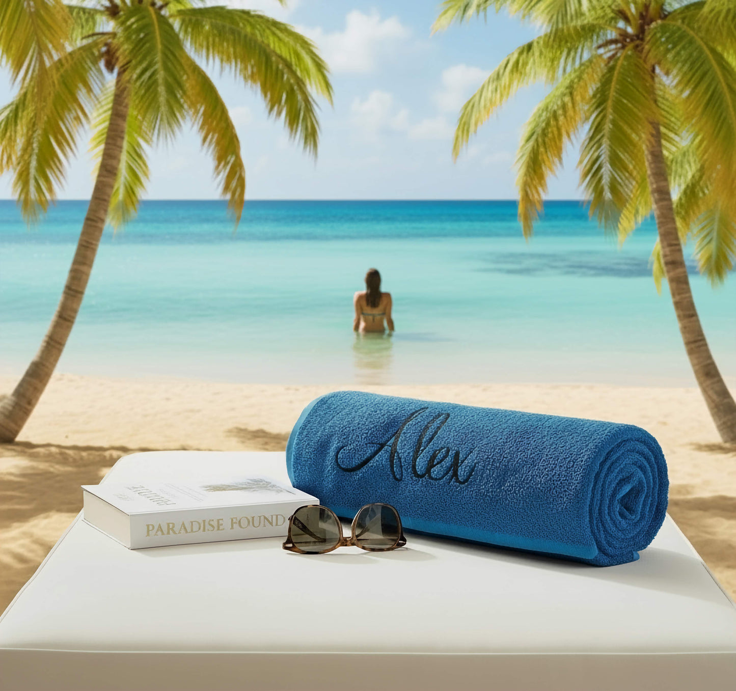 A blue towel on a sunbed with book & sunglasses in a beach scene