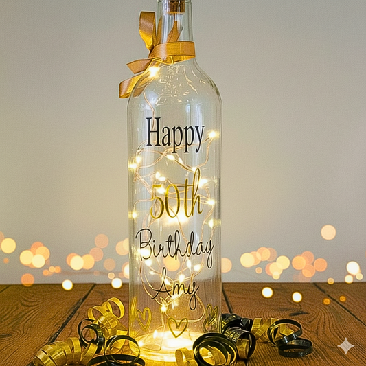 Decorative bottle with 'Happy 50th Birthday Amy' text and string lights on a wooden surface.