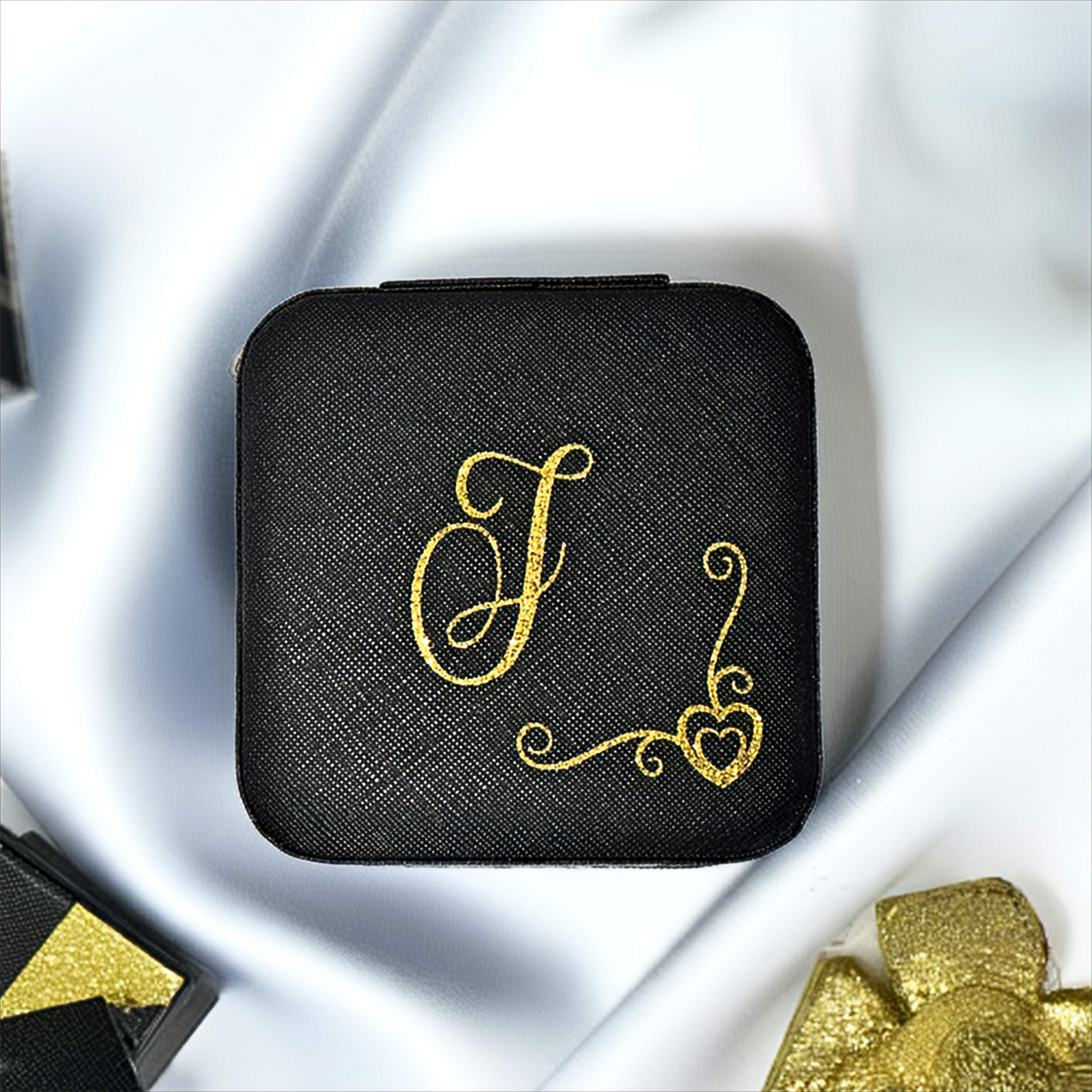 Black square box with gold monogram on a white fabric background