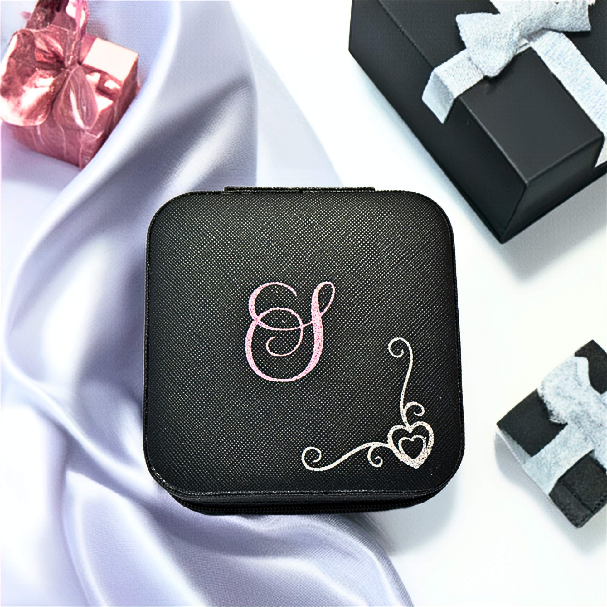 Black jewelry case with pink and silver decorative elements on a white fabric background