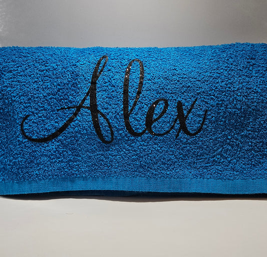 Royal blue beach towel with the name 'Alex' in black glitter vinyl on the edge