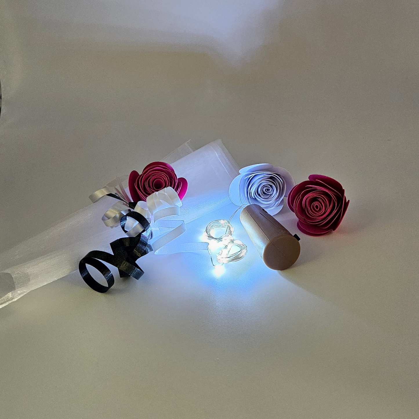 Led ice white bottle lights next to an organza gift bag & satin curling ribbons on a white background