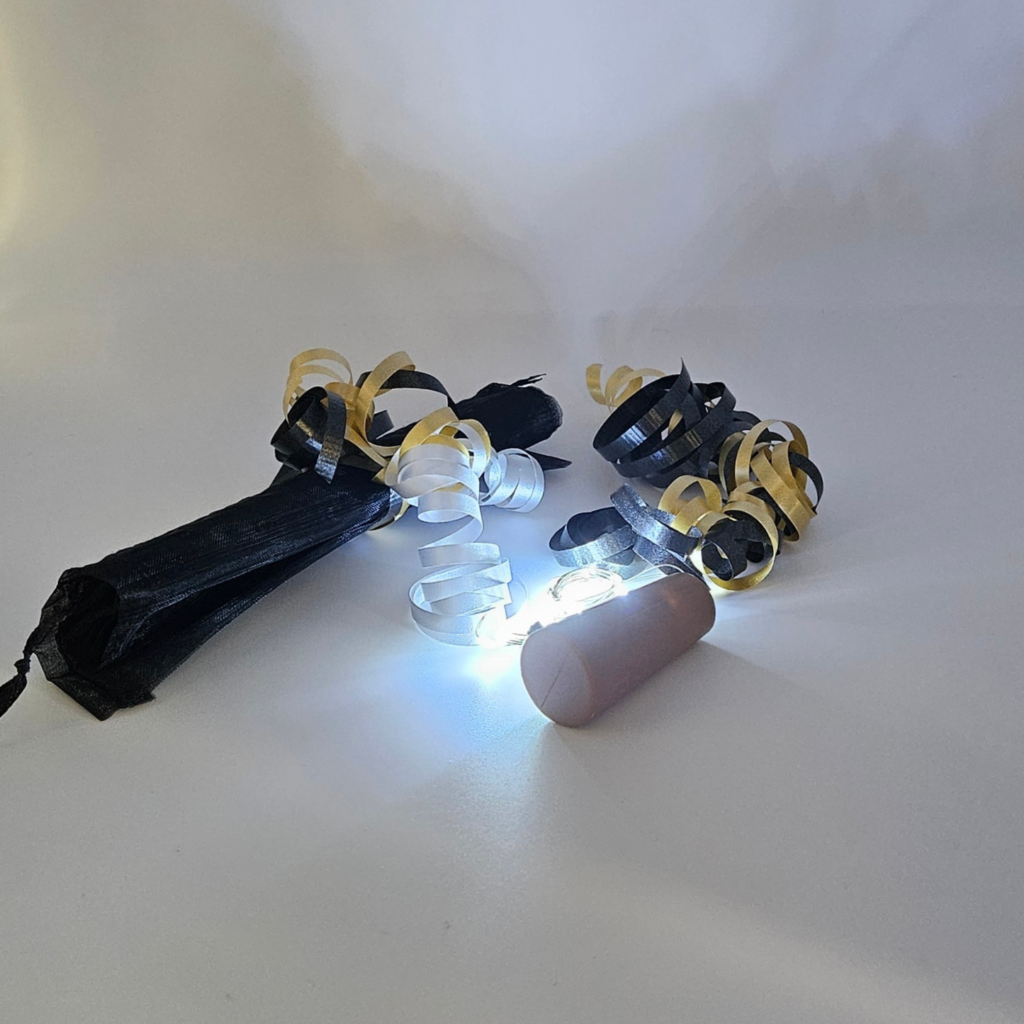 LED ice white bottle lights next to an organza gift bag & satin curling ribbons on a white background