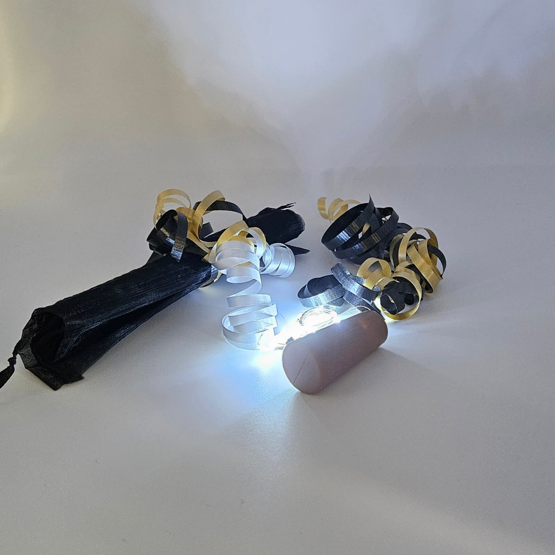 LED ice white bottle lights next to an organza gift bag & satin curling ribbons on a white background