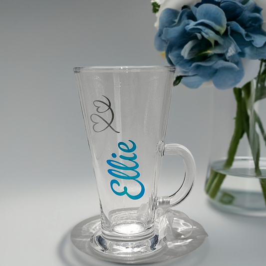 Personalised luxury latte, coffee & hot chocolate glass gifts for her. Perfect for her birthday, special occasions, and Mother's Day. Decorated with a name in a chrome peacock blue vinyl with a silver glitter heart swirl.