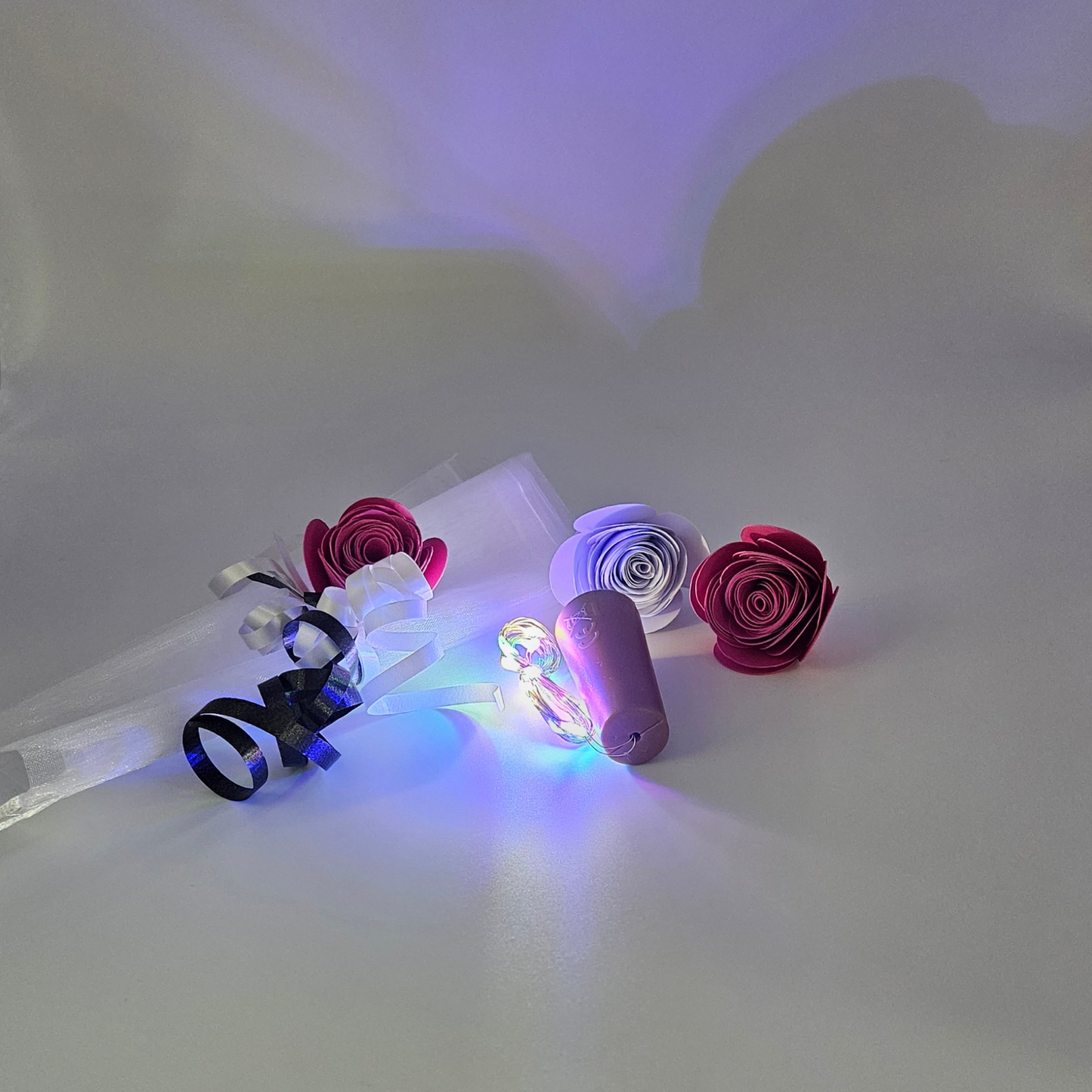 Multicoloured LED bottle lights next to an organza gift bag & satin curling ribbons