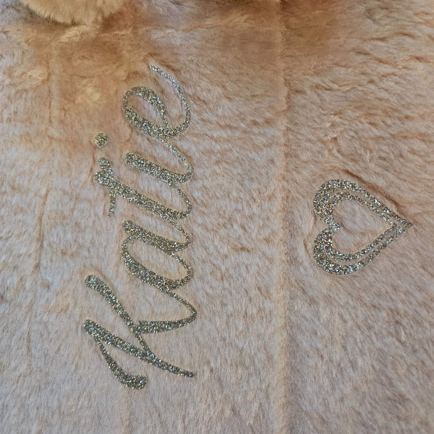 A pink faux fur cover with the name  'Katie' & heart design in silver glitter vinyl.