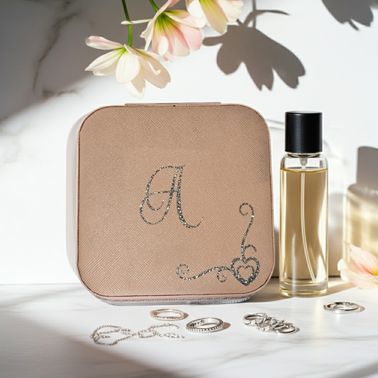 Personalised pink square jewellery box with the initial 'A' on it with a heart swirl border in silver glitter vinyl. Placed on a white marble surface next to small jewellery pieces and a purfume bottle.
